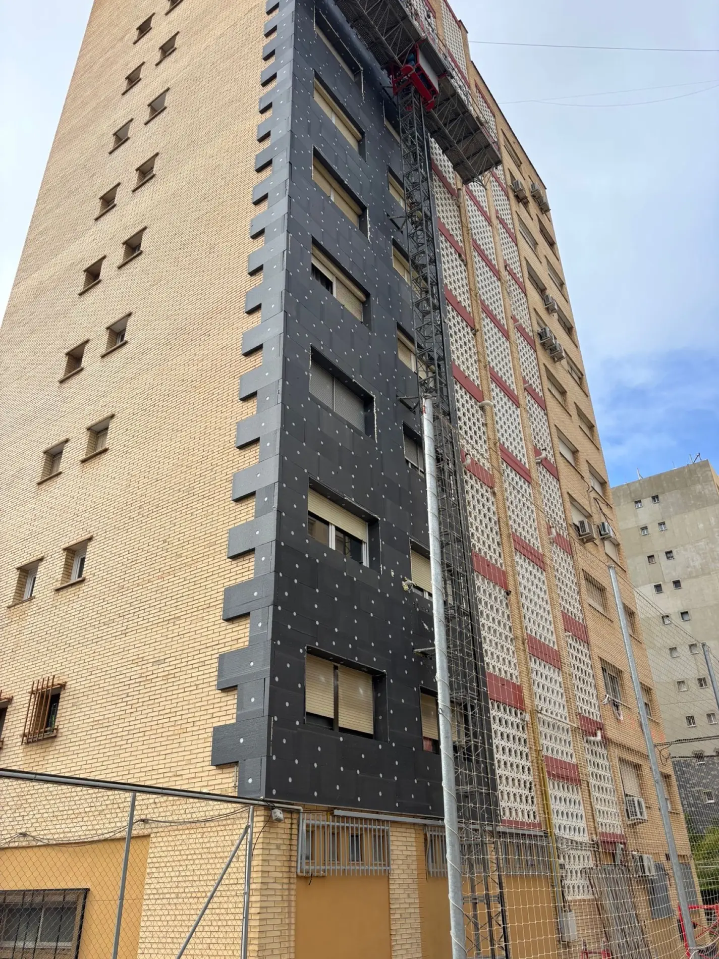 Edificio a media intervención: media fachada con el ladrillo original y media con el aislamiento colocado
